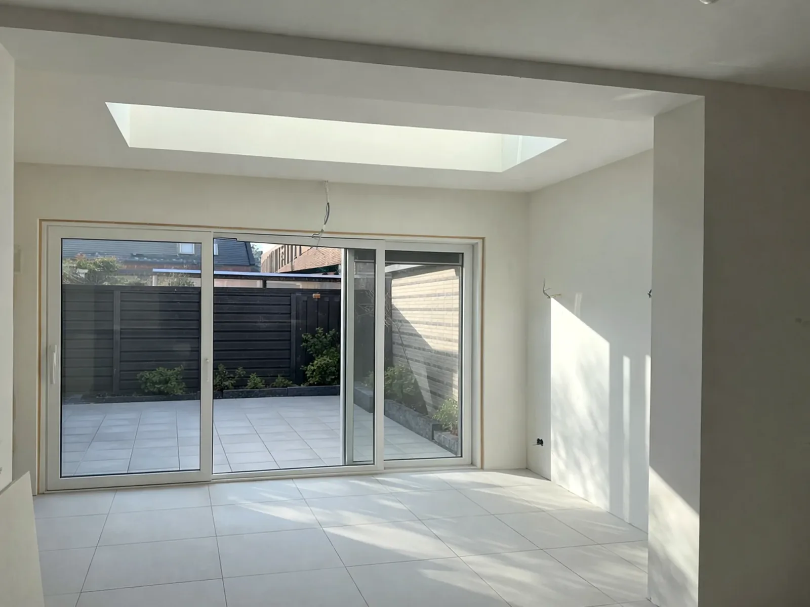 De afgeronde aanbouw van binnen, met een lichtstraat in het plafond en een schuifpui naar de tuin.
