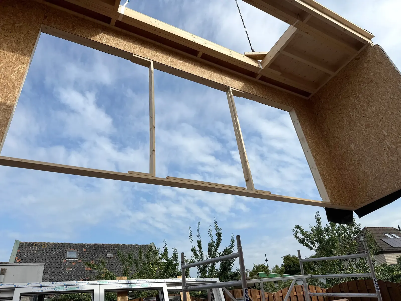 Het element hangt aan de kraan, van onderaf gezien door de nog lege raamopeningen.