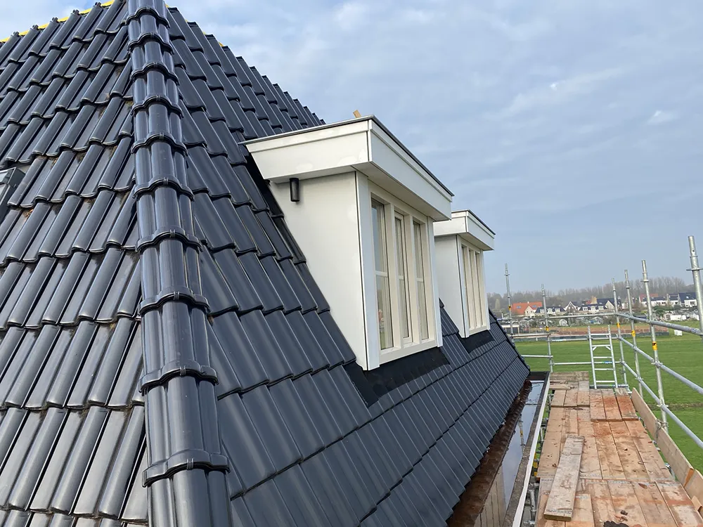 Twee prefab dakkapellen naast elkaar op het schuine dak, gezien vanaf de steiger.